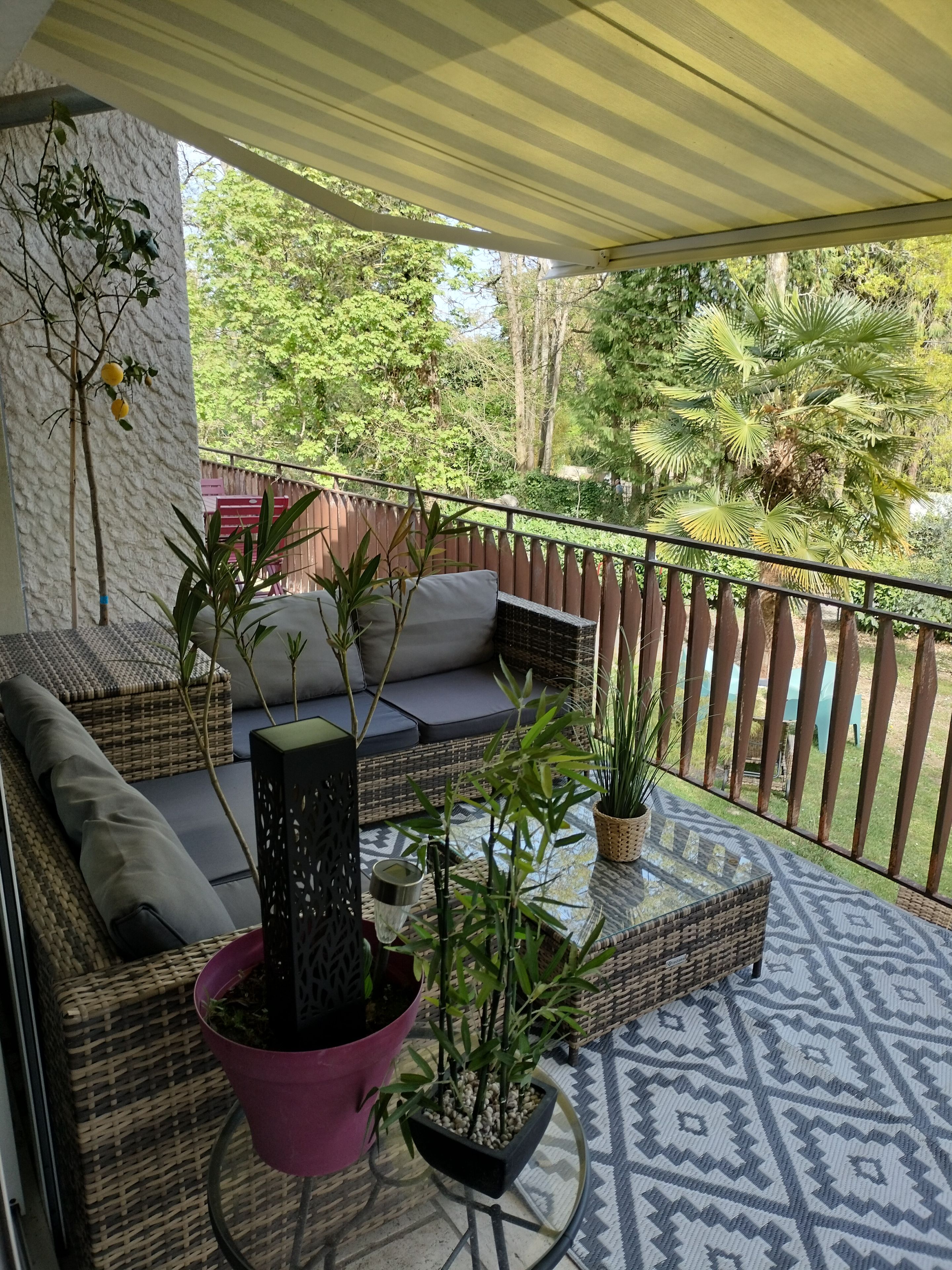Een overdekt terras met rieten meubels en plantenpotten.