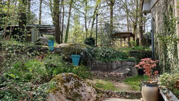 A stone staircase leading up to a wooden structure, surrounded by lush greenery and trees.