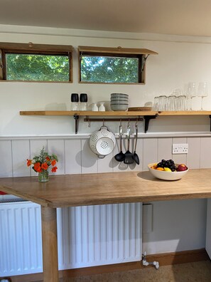 A kitchen with wooden countertops, a window above the sink, and a bowl of fruit on the counter.