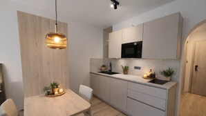 A modern kitchen with a built-in microwave, a dining table with chairs, and a pendant light. - New modern apartments for active vacationers with wellness and pool. Dog friendly (Goldrain)
