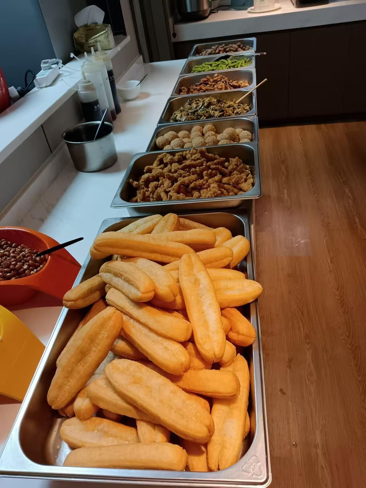 A buffet with various food items, including fried chicken, vegetables, and bread rolls.