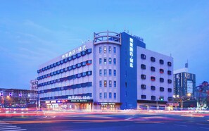 Ein mehrstöckiges Hotel mit Hinweisschildern für 'Jinglai Hotel' und 'Wenge Hotel'.