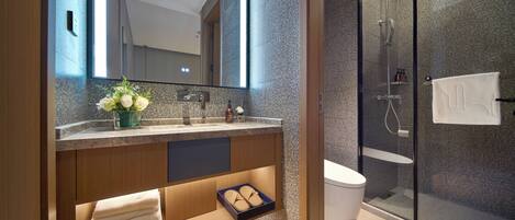 A modern bathroom with a large mirror, dual sinks, a shower enclosure, and a built-in towel rack.