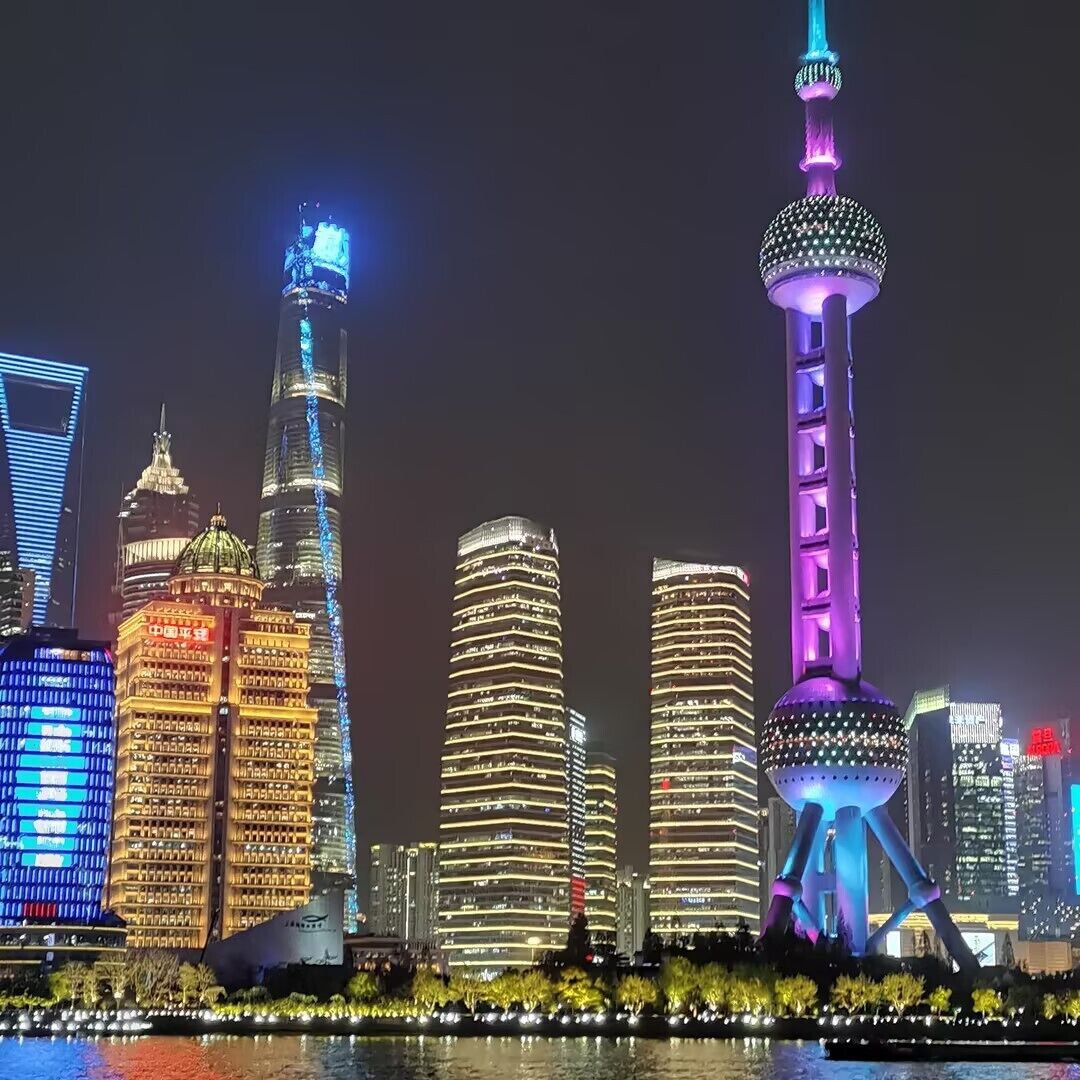 A city skyline with illuminated buildings at night.