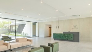 Un espace d’accueil moderne avec un comptoir en marbre vert, un canapé beige et un fauteuil vert.