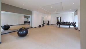 Une salle de sport spacieuse, équipée de matériel d’exercice, de miroirs et dotée d’un design moderne et épuré.