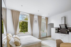 Ein Schlafzimmer mit Bett, Schreibtisch und einer Küchenzeile.