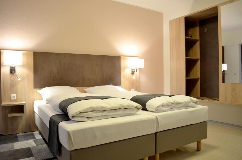 Un lit double avec deux oreillers, des tables de chevet avec des lampes, une armoire et un miroir.