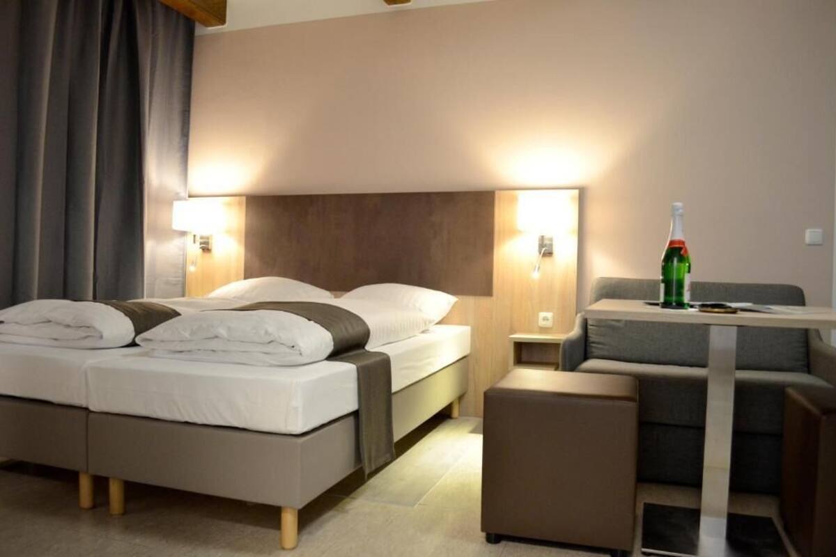 Una camera d'albergo con due letti, un tavolino e una sedia.