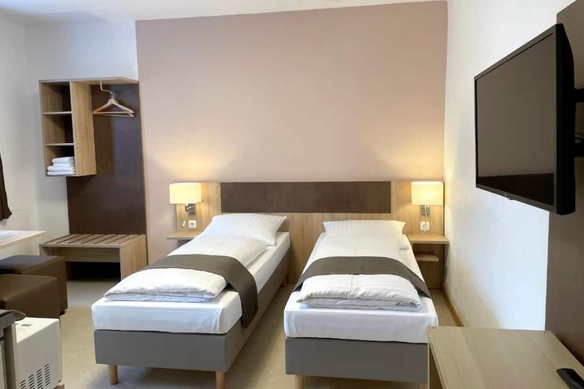 Una camera d'albergo con due letti, una televisione, una scrivania e un armadio.