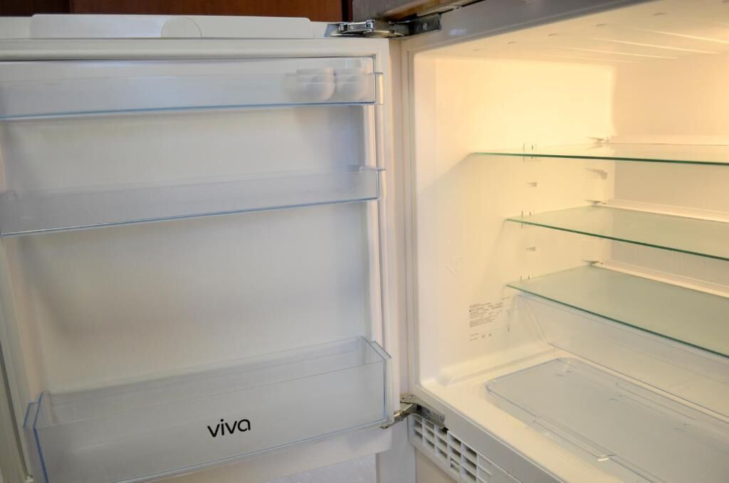 Uma geladeira aberta com prateleiras transparentes e a marca 'viva' visível.