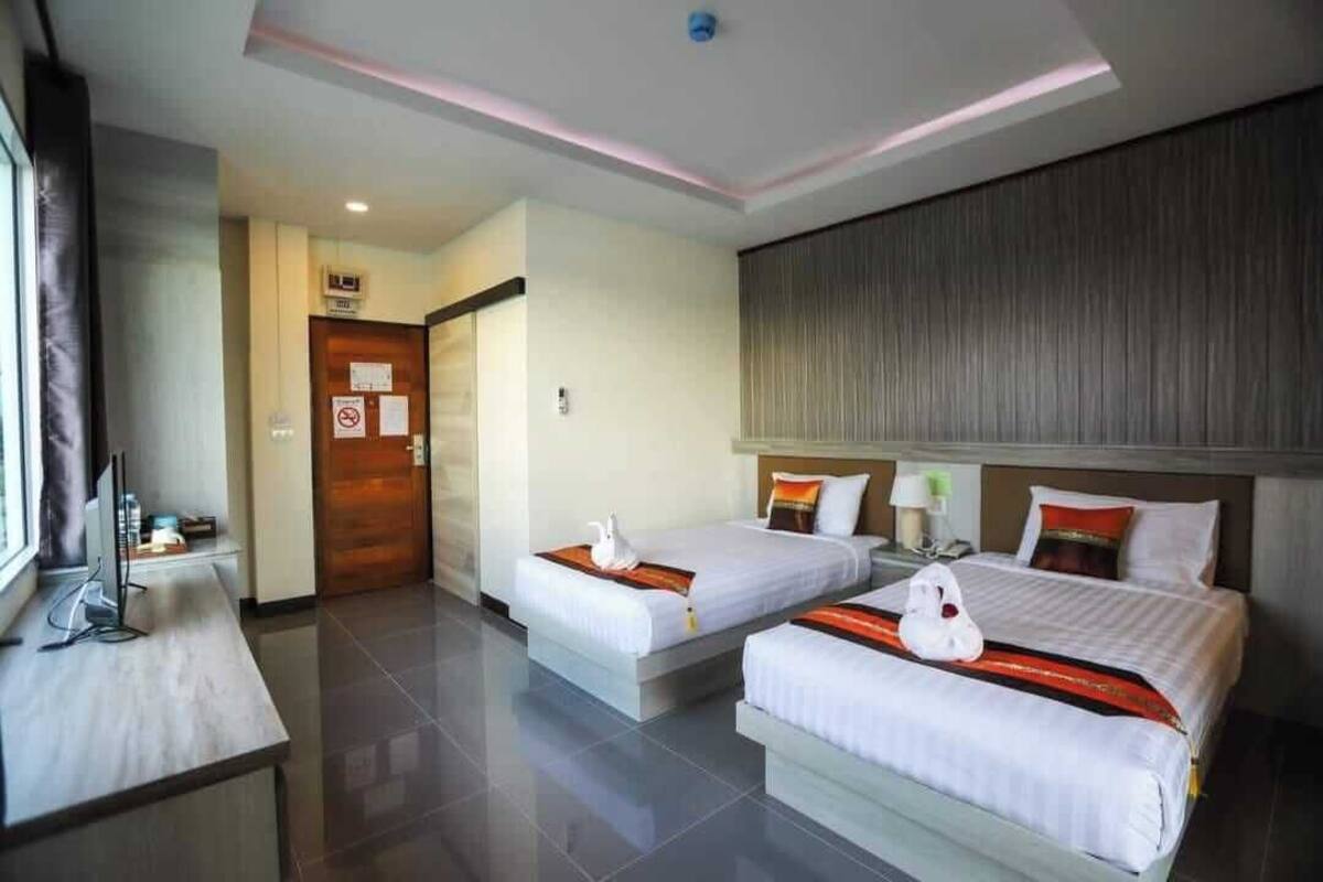 Quarto de hotel com duas camas, uma escrivaninha e uma televisão.