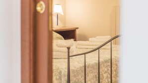 Una habitación de hotel con una cama, una mesita de noche, una lámpara y un espejo.