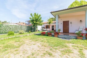 A residential property with a garden, a white exterior, a brown door, and a small patio area with outdoor furniture. - Titti Tourist Lodging (Bolsena)