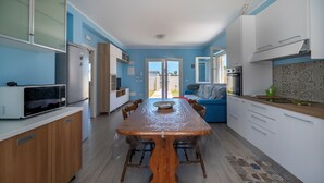 Una cocina moderna con una mesa de comedor de madera, armarios blancos y una pared azul.