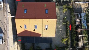 Une vue aérienne d’un bâtiment doté d’un toit rouge, de sections numérotées et d’un sol recouvert de gravier.
