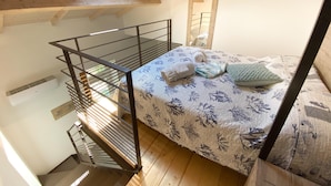 Une chambre de dortoir avec un lit superposé, une lucarne, un escalier en bois et un miroir.