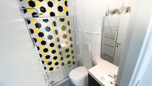 Une salle de bain moderne avec une douche à parois de verre, des toilettes blanches et un meuble-lavabo avec un miroir.