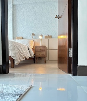 A bedroom with a bed, bedside table, lamp, and a patterned wall. - Pond & Sea View, Mactan Strait (Lapu-Lapu)