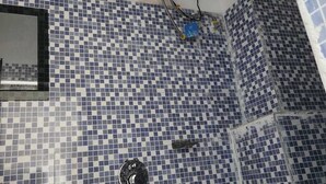 A bathroom with blue and white checkered tiles, a white sink, and a shower with a black faucet. - ANAYA GUEST HOUSE & RESTAURANT ETAH (Etah)