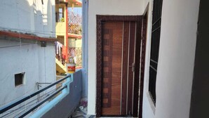 A narrow corridor with patterned tiles, a metal railing, and a door with a metal grill. - ANAYA GUEST HOUSE & RESTAURANT ETAH (Etah)