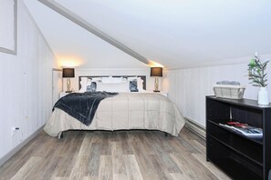 Une chambre à coucher avec un lit, des lampes de chevet, une table de chevet, une bibliothèque et une plante en pot.