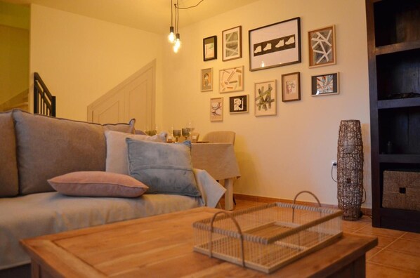 Una sala de estar con un sofá, una mesa de centro y una pared decorada con cuadros.