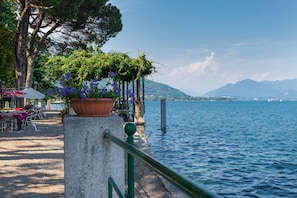 A lakeside terrace with outdoor seating and a view of the lake and mountains. - Casa Mirella Full AC And Terrace (Nebbiuno)