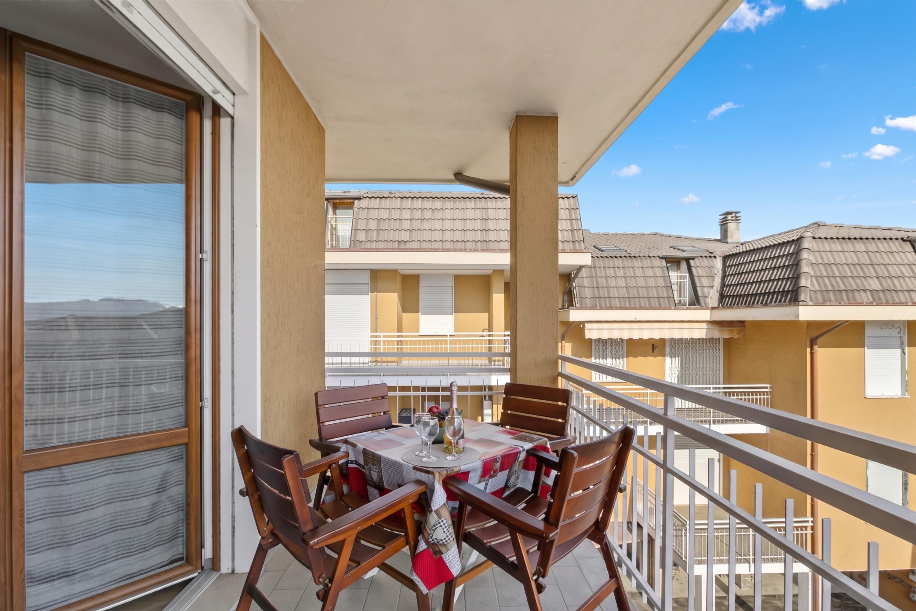 Ein Balkon mit einem Tisch für vier Personen, umgeben von Holzstühlen.