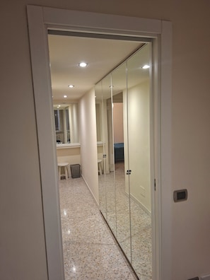 A hallway with a mirrored closet door, a white toilet, and a small stool. - Spacious and bright apartment located in the center of Rome. (Roma)