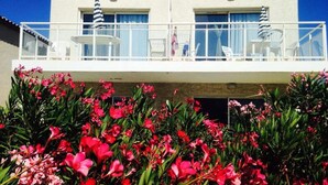 A hotel with a balcony, outdoor seating, and a variety of flowering plants. - Apartment in Gruissan Near Clape Mountain (Gruissan)