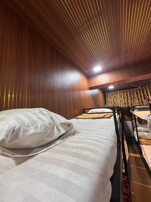 Een kamer met houten lambrisering, een stapelbed en een raam met gordijnen.