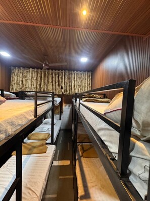 Ein Schlafsaalzimmer mit Etagenbetten, Holzwandverkleidung und einem Vorhang.