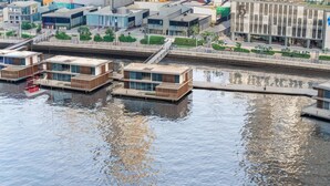 En modern fastighet vid vattnet med flytande hus som är sammanlänkade med gångvägar.