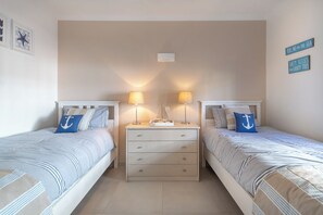 A bedroom with two beds, a nightstand between them, and wall-mounted lamps. - Stunning beach house, panoramic views across Meia Praia bay (Lagos)