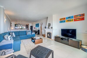 Una sala de estar moderna con un sofá azul, una mesa de centro, un televisor y una chimenea.