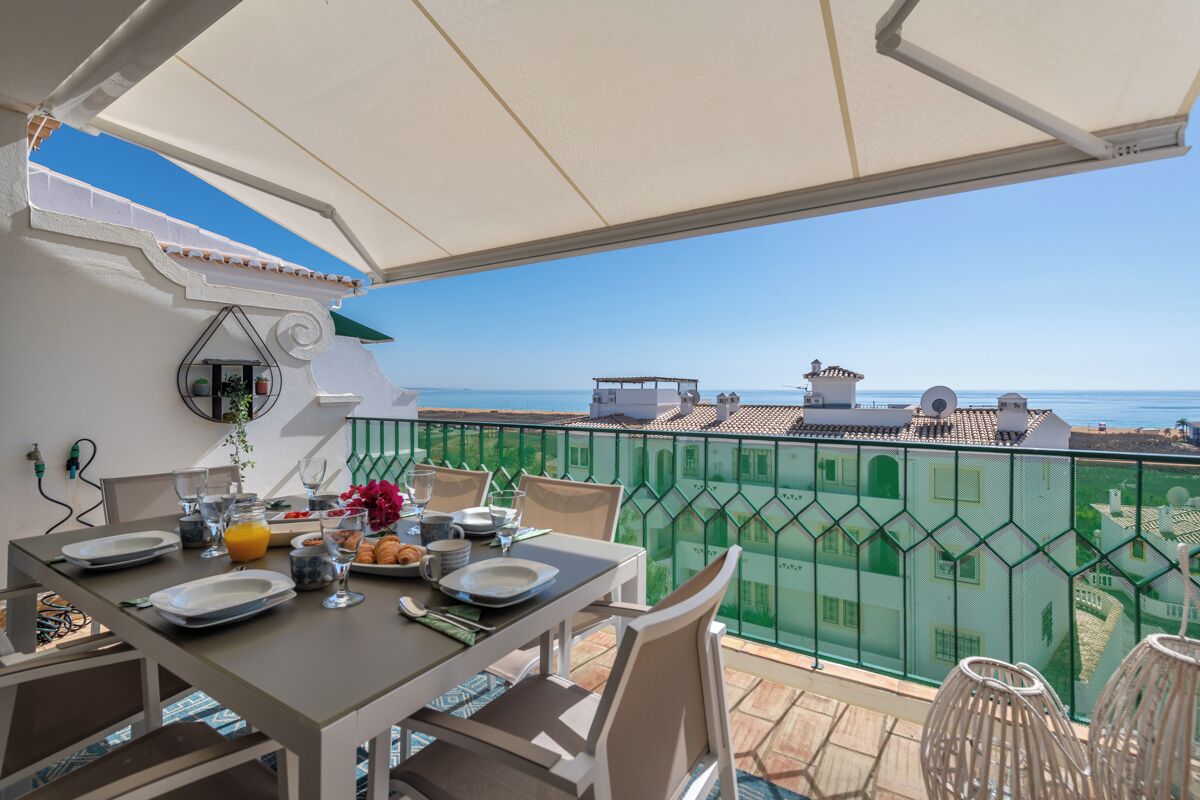 Ein Balkon mit Frühstückstisch und Blick auf die Küste.