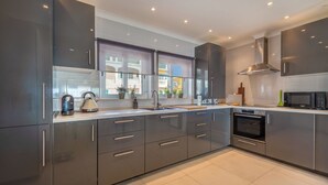 A modern kitchen with stainless steel appliances, a large window, and a view of the city. - Stunning beach house, panoramic views across Meia Praia bay (Lagos)