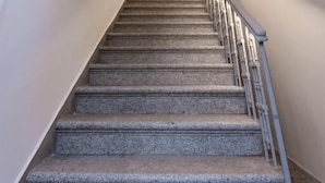 Un escalier avec une rampe, un luminaire au plafond et une vue sur l’escalier.