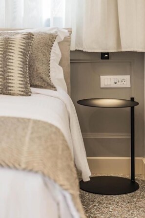 A bedroom with a bed, a round table, and a wall socket.