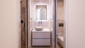 Une salle de bain moderne avec un lavabo sur colonne, un miroir et un espace douche.