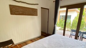 A bedroom with a large bed, wooden floor, a view of the outdoors through a sliding door, and a curtain. - Aonang green tree (Krabi)