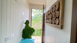 A narrow hallway with wooden flooring, a blue bench, a kettle, and a large plant. - Aonang green tree (Krabi)