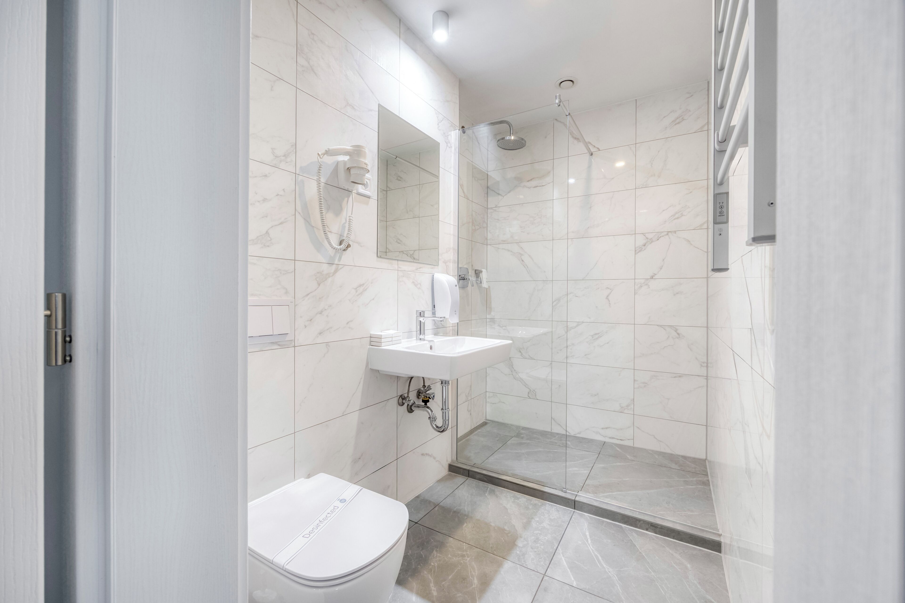 Une salle de bain moderne équipée de toilettes, d’un lavabo, d’un miroir et d’une douche.