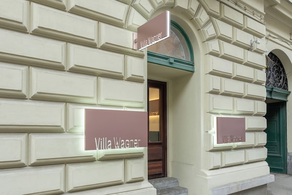 A building facade with "Villa Wagner" signs, a green door, and a window with decorative moldings.