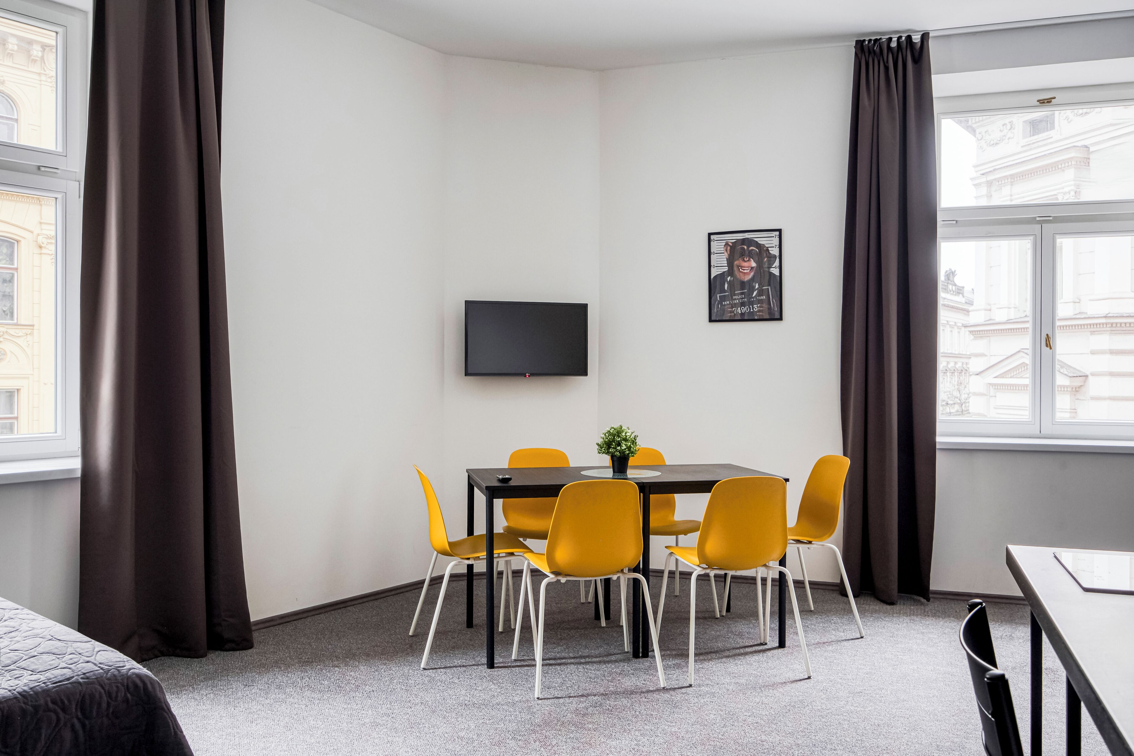Een hotelkamer met een bed, een tafeltje met stoelen, een televisie en een raam met gordijnen.