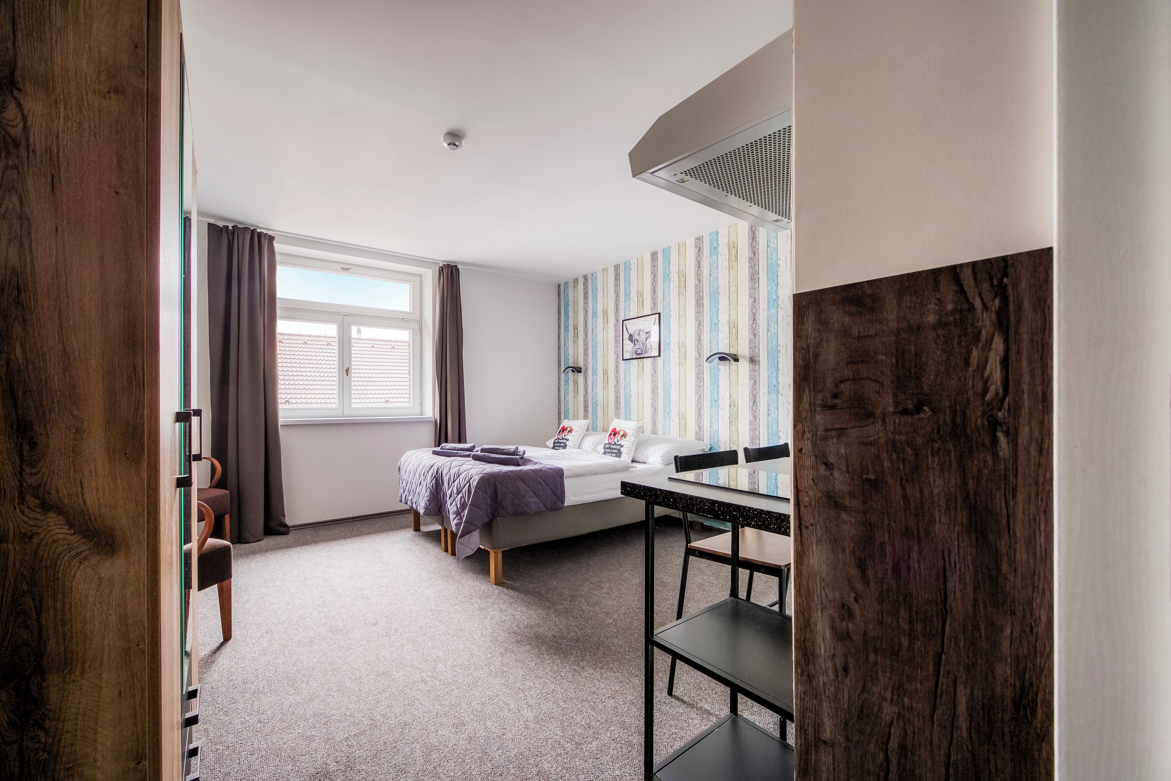 A bedroom with a bed, a desk, a chair, a window, and a curtain.
