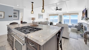 Un'ampia cucina con una grande isola, illuminazione a sospensione moderna e un ventilatore a soffitto.