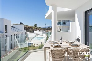 A modern outdoor dining area with a pool view, white architecture, and wicker chairs. - Lana | Sea view - terrace - fuengirola (Fuengirola)