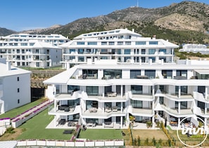 A modern multi-story hotel with balconies, a well-maintained lawn, and a mountainous backdrop. - Lana | Sea view - terrace - fuengirola (Fuengirola)